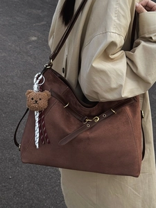 Borsa tote in pelle scamosciata marrone con ciondolo a orsetto su modella