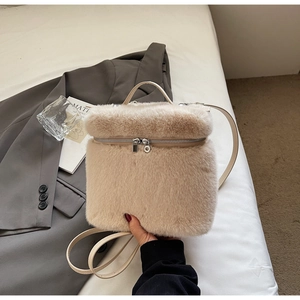 Detailed view of beige faux fur backpack with silver zippers on a white soft surface