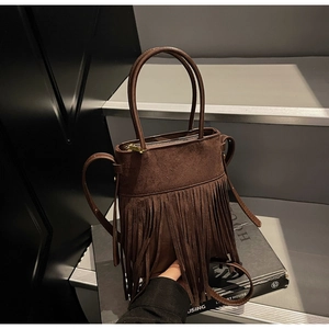 Détail du sac seau en daim marron foncé avec de longues franges et poignées rondes