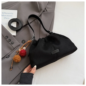 Détail du sac hobo en daim noir avec pampilles colorées et logo de la marque sur costume