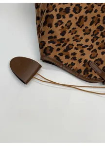 Détail du sac cabas léopard avec pendentif cœur en cuir marron et coutures précises