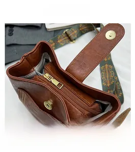 Detail view of the smooth zipper closure and fabric lining on this brown leather bucket bag