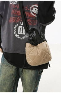 Quilted nylon drawstring bucket bag shown on a model with adjustable black shoulder strap