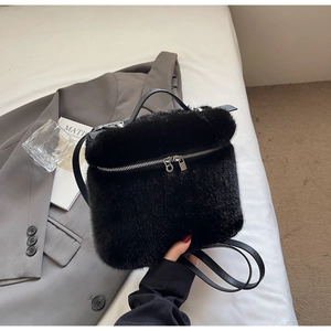 Handheld view of a plush black faux mink fur bucket bag with silver metal dual zippers