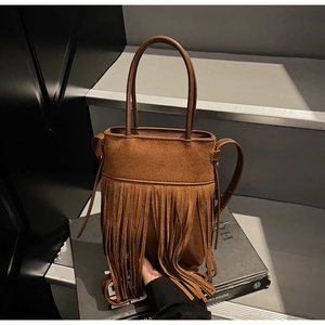 Détail de la texture en daim marron et des franges en cuir sur le sac seau vintage