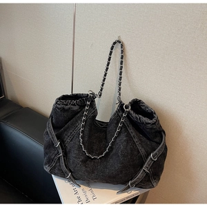 Macro shot of black denim tote with metallic chain strap and side buckle detail