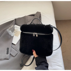 Detail of black faux fur handbag with dual silver zippers and leather strap