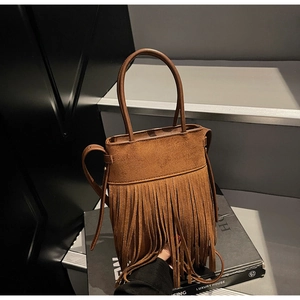 Détail du sac seau vintage en daim marron foncé avec de longues franges et anse