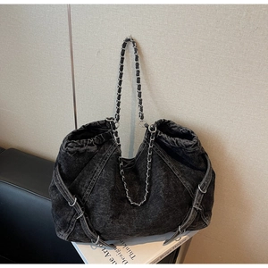 Detail of black washed denim tote bag showing vintage texture and silver chain strap