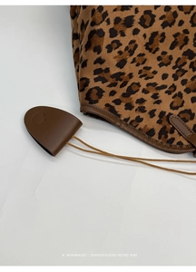 Détail macro du sac cabas léopard avec garniture en cuir marron et pendentif incurvé