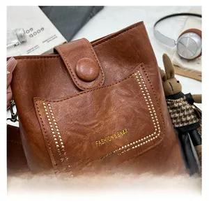 Detail of vintage brown bucket bag with FASHION & BAGS text and ethnic style wide strap