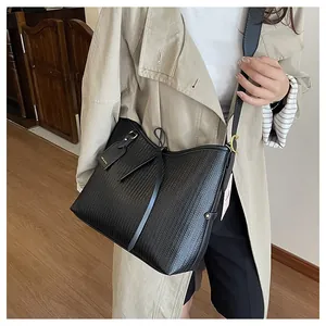 Dettaglio della trama intrecciata nera e del pendente dorato su questa borsa tote