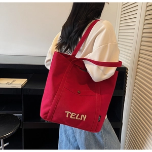 Détail d'un grand sac fourre-tout rouge en toile avec écusson TELN et large bandoulière
