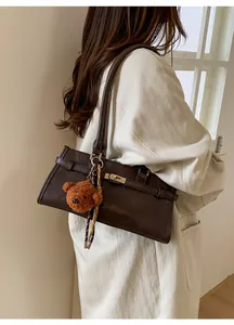 Macro shot of dark brown retro leather tote bag with metal buckle and plush bear charm