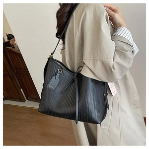 Dettaglio della borsa tote nera intrecciata con nappe in pelle e rifiniture dorate