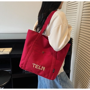 Détail du grand sac cabas en toile rouge avec broderie 3D et poche avant à bouton-pression