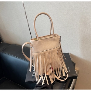 Vue détaillée des longues franges denses et de la texture en daim doux du sac beige