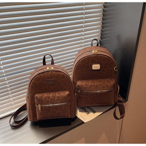 Detail showing two sizes of brown leopard print backpacks with gold zippers and brand logo