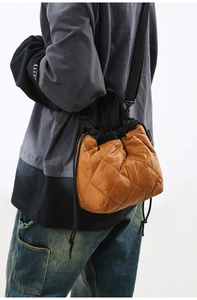 Side view of caramel quilted bucket bag with black drawstring and adjustable strap