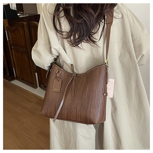 Dettaglio della borsa tote in pelle marrone con elegante targhetta e tracolla in pelle