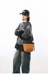 Detail of quilted orange-brown bucket bag with black drawstring and nylon texture