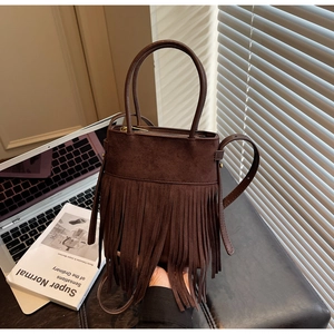 Gros plan détaillé du sac seau en daim marron foncé avec de longues franges et fermeture