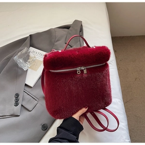 Detail of burgundy faux fur backpack with silver zipper on a grey blazer jacket