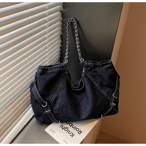 Detail of blue denim tote bag with metal chain straps and decorative silver rings
