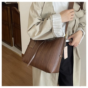 Vista dettagliata della trama intrecciata marrone scuro e del tag di una borsa tote