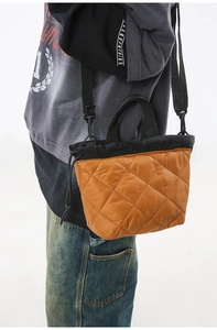 Detail of orange quilted nylon crossbody bag with black drawstrings and shoulder strap