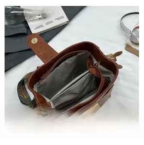 Detail of vintage brown bucket bag showing internal zipper compartment and ethnic strap