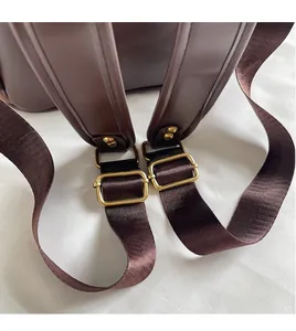 Detail of adjustable brown leather straps with gold metal buckles on leopard backpack