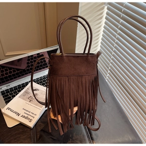Détail du sac seau en daim marron foncé avec de longues franges et bandoulière