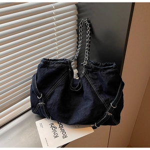Detailed shot of dark blue denim tote bag with drawstring closure and metal chain strap