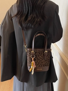 Chic leopard print bucket bag with dual handles and wooden bead charm accessory
