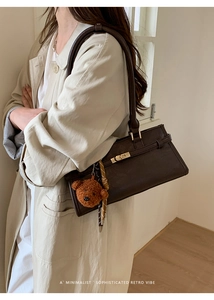 Detail of dark brown tote bag featuring gold hardware and a cute plush bear charm