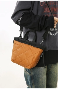 Detail of quilted brown bucket bag featuring sleek stitching and branded woven label
