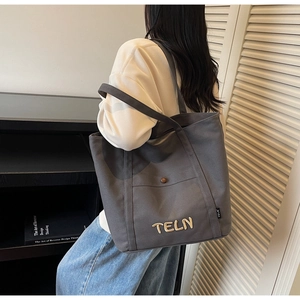 Détail du grand sac cabas en toile gris foncé avec poche avant et décor de lettres