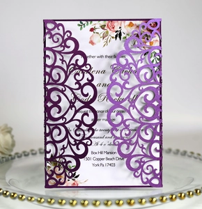 Detail of laser-cut purple lace wedding invitation with floral inner card on glass tray