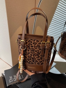 Leopard print bucket bag with brown leather trim and decorative tassel charm