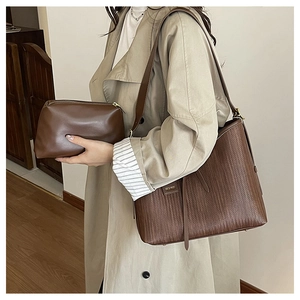 Dettaglio borsa shopper intrecciata marrone scuro con pochette abbinata e finiture dorate