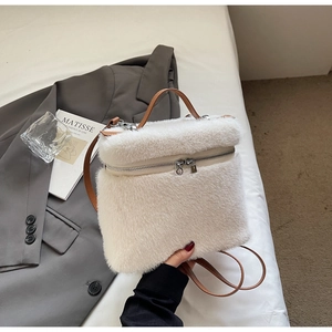 Detailed close-up of fluffy white faux fur backpack with brown leather handles and silver zippers