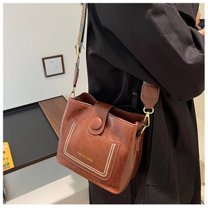 Detail view of brown vintage bucket bag with ethnic woven strap and gold lettering