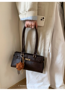 Detail of retro coffee brown handbag with lychee texture and cute plush bear charm