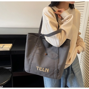 Détail du sac cabas en toile grise avec poche avant et broderie 3D TELN de marque