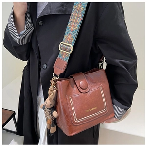 Brown vintage leather bucket bag with colorful woven strap and cute bear charm pendant