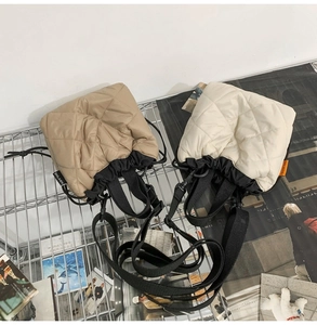 Close-up of quilted nylon bucket bags in khaki and beige with contrast black trim and straps