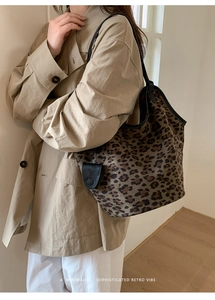 Détail du sac cabas léopard avec lanières en cuir noir porté avec un trench-coat beige