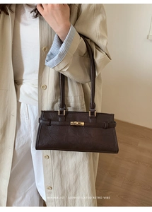 Close-up of retro dark brown lychee leather handbag with signature gold metal buckle