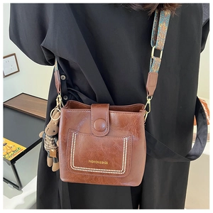 Detail of retro dark brown bucket bag with ethnic style strap and bear charm